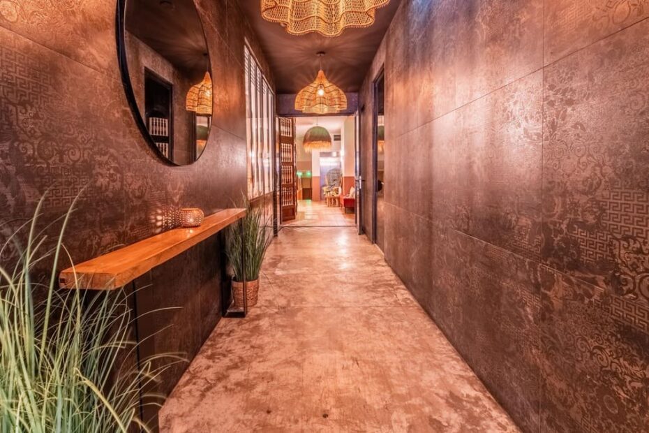 Couloir d'un spa aux murs texture cuivre, avec suspensions en osier et plantes vertes